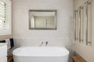a white bath tub in a bathroom with a mirror at Verona in Shoal Bay +12 photos