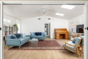 a living room with two blue couches and a piano at Verona in Shoal Bay