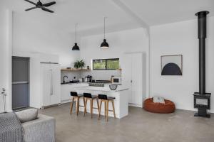 a white kitchen with bar stools and a couch at Tathra Bermagui Road 613 in Tathra