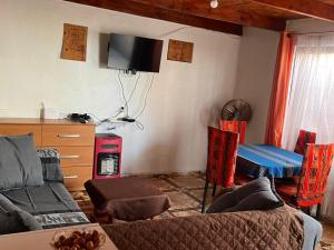 a living room with a couch and a tv on the wall at Estrella Ancestral in San Pedro de Atacama