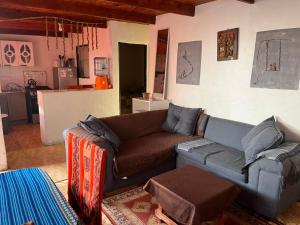 a living room with a couch and a kitchen at Estrella Ancestral in San Pedro de Atacama