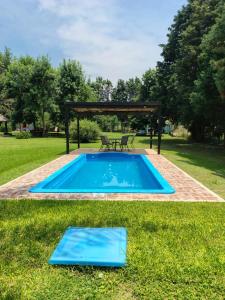 a swimming pool in the grass with a table and a picnic table at Quinta con pileta y quincho in Fátima