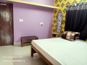 ein Schlafzimmer mit einem Bett in einem Zimmer mit lila Wänden in der Unterkunft Swpnaneer home stay in Shānti Niketan
