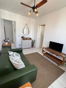 a living room with a green couch and a ceiling fan at Apartamento no centro com ar-condicionado in Piracicaba +21 photos