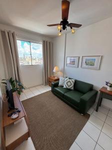 a living room with a green couch and a ceiling fan at Apartamento no centro com ar-condicionado in Piracicaba
