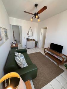a living room with a green couch and a ceiling fan at Apartamento no centro com ar-condicionado in Piracicaba