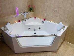 a large white tub in a bathroom with pink candles at Apartamenty Lux Chorzów in Chorzów +19 photos