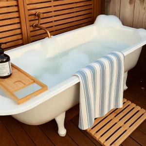 een badkuip met een handdoek op een houten vloer bij Plum Coastal Cottage in Raumati Beach