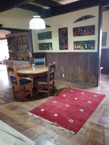 una sala da pranzo con tavolo, sedie e tappeto rosso di Fazenda Vista Soberba a Nova Friburgo