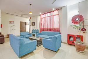 a living room with blue chairs and a fireplace at Super Hotel O Glorious Stayz in Noida