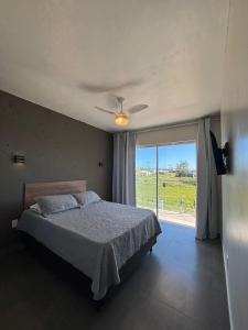 een slaapkamer met een bed en een groot raam bij Pousada Garden in Tramandaí