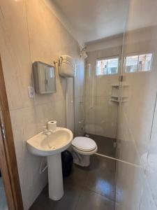 een badkamer met een toilet, een wastafel en een douche bij Pousada Garden in Tramandaí