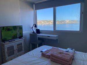 a bedroom with a bed and a tv and a window at La Herradura Mágica descansa y disfruta en familia in Coquimbo