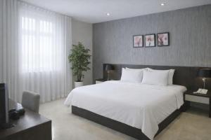 a bedroom with a large white bed and a tv at Golden Queen Aparthotel in Ho Chi Minh City +8 photos
