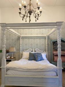 una camera con letto bianco e lampadario pendente di Ducks & Drakes Outback House a Broken Hill