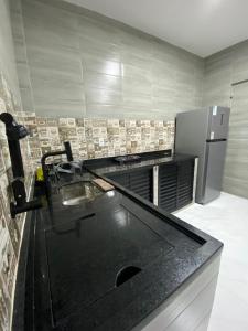 een keuken met een zwart aanrechtblad en een koelkast bij Sua Estadia Angra in Angra dos Reis