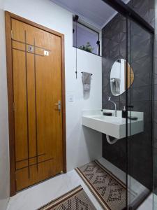 een badkamer met een wastafel en een houten deur bij Sua Estadia Angra in Angra dos Reis