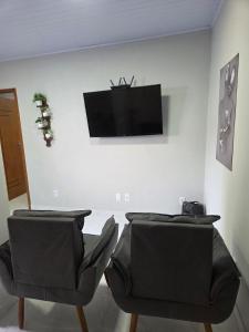 twee stoelen in een kamer met een tv aan de muur bij Sua Estadia Angra in Angra dos Reis