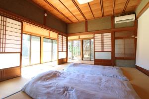 een slaapkamer met een groot bed in een kamer met ramen bij 白子ハウス in Goi