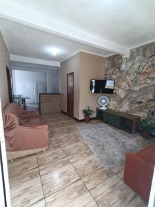 a living room with a couch and a tv on a stone wall at Bela Casa em Madre de Deus 2 in Madre de Deus