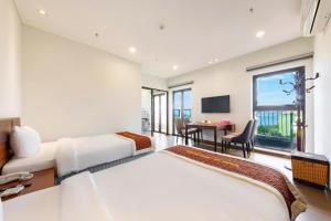 ein Hotelzimmer mit 2 Betten und einem Tisch mit einem Schreibtisch in der Unterkunft D26 Nha Trang Hotel in Nha Trang