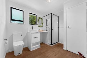 een badkamer met een toilet, een wastafel en een spiegel bij Henderson Oasis in Auckland