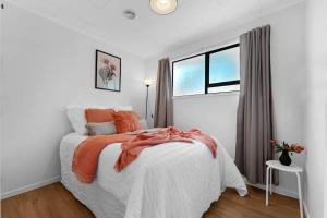 een witte slaapkamer met een bed en een raam bij Henderson Oasis in Auckland