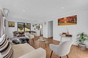 een woonkamer met een bank en stoelen bij Henderson Oasis in Auckland
