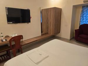 a living room with a table and a tv on the wall at Hotel GT Galaxy in Chennai