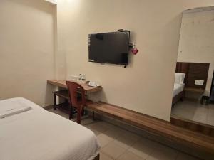 a hotel room with a desk and a tv on the wall at Hotel GT Galaxy in Chennai