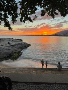 een groep mensen die bij zonsondergang op het strand lopen bij Refúgio à Beira Mar Na Praia da Tartaruga in Rio das Ostras
