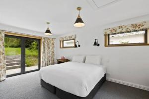 a bedroom with a white bed and a window at Lakeside Bliss Homestead with outdoor spa in Queenstown