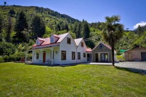 a white house with a palm tree in a yard at Lakeside Bliss Homestead with outdoor spa in Queenstown