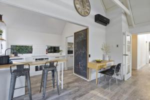 une cuisine avec une table et des chaises et une horloge au mur dans l'établissement Panoramic Farmhouse theme with shared spa pool, à Queenstown