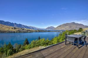 ein Tisch und Stühle auf einer Terrasse mit Blick auf einen See in der Unterkunft A Surprise on Sunrise - luxury with sauna and spa in Queenstown