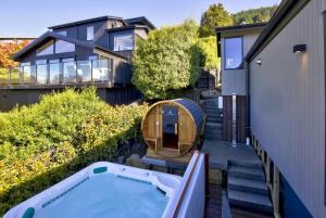 einen Hinterhof mit einem Whirlpool und einem Haus in der Unterkunft A Surprise on Sunrise - luxury with sauna and spa in Queenstown + 13 Fotos