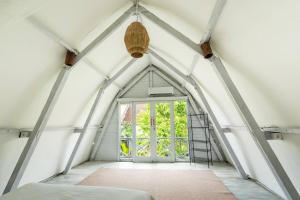 een zolderkamer met een raam en een ladder bij Villa Tropical A in Uluwatu