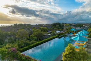 a large swimming pool with blue umbrellas on a resort at Rama Residence Padma in Legian
