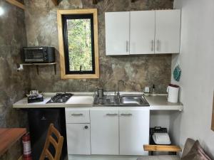 a kitchen with white cabinets and a sink and a window at Espacio Bosque La Quemada in Puerto Varas