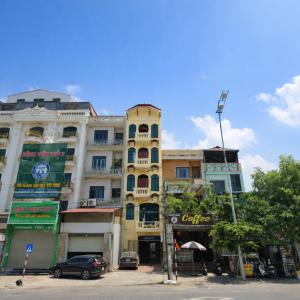 ein hohes gelbes Gebäude mit davor geparkten Autos in der Unterkunft Bắc Ninh Nhà Nghỉ Hà Thành - 北宁河城賓館 in Bắc Ninh