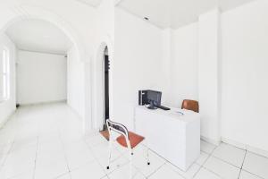 a white room with a chair and a tv on a cabinet at RedDoorz at Hotel Lavender Kertajati in Gadel