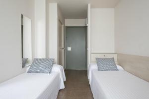 two beds in a room with white walls at Residencia Universitaria Manuel Agud Querol in San Sebastián