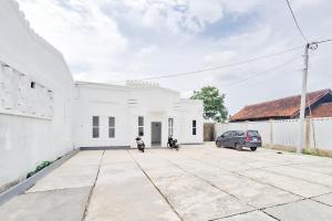 a white building with two motorcycles parked in a parking lot at RedDoorz at Hotel Lavender Kertajati in Gadel
