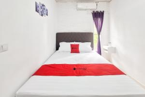 a bed in a room with a red pillow on it at RedDoorz at Hotel Lavender Kertajati in Gadel