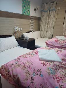 two beds in a hotel room with pink sheets at Everest Base Cam Hostel in Hong Kong