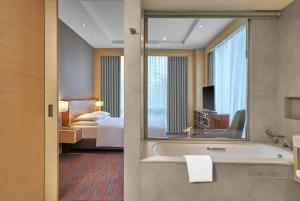 勒克瑙Hyatt Regency Lucknow Gomti Nagar的一间带浴缸的浴室和一间带床的卧室