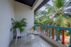 d'un balcon avec une table, des chaises et un palmier. dans l'établissement The Baga Pescador -TBV, à Baga