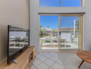 ein Wohnzimmer mit Flachbildfernseher und Tisch in der Unterkunft Cabarita Barefoot Beach House in Cabarita Beach