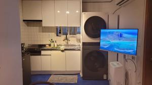a kitchen with a tv on the wall and a washing machine at Maison de Jann in Seoul