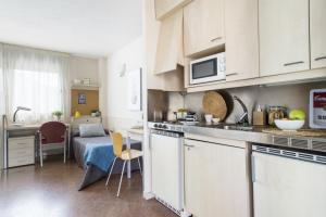 a kitchen with white cabinets and a table with a bed at Residencia Universitaria Manuel Agud Querol in San Sebastián